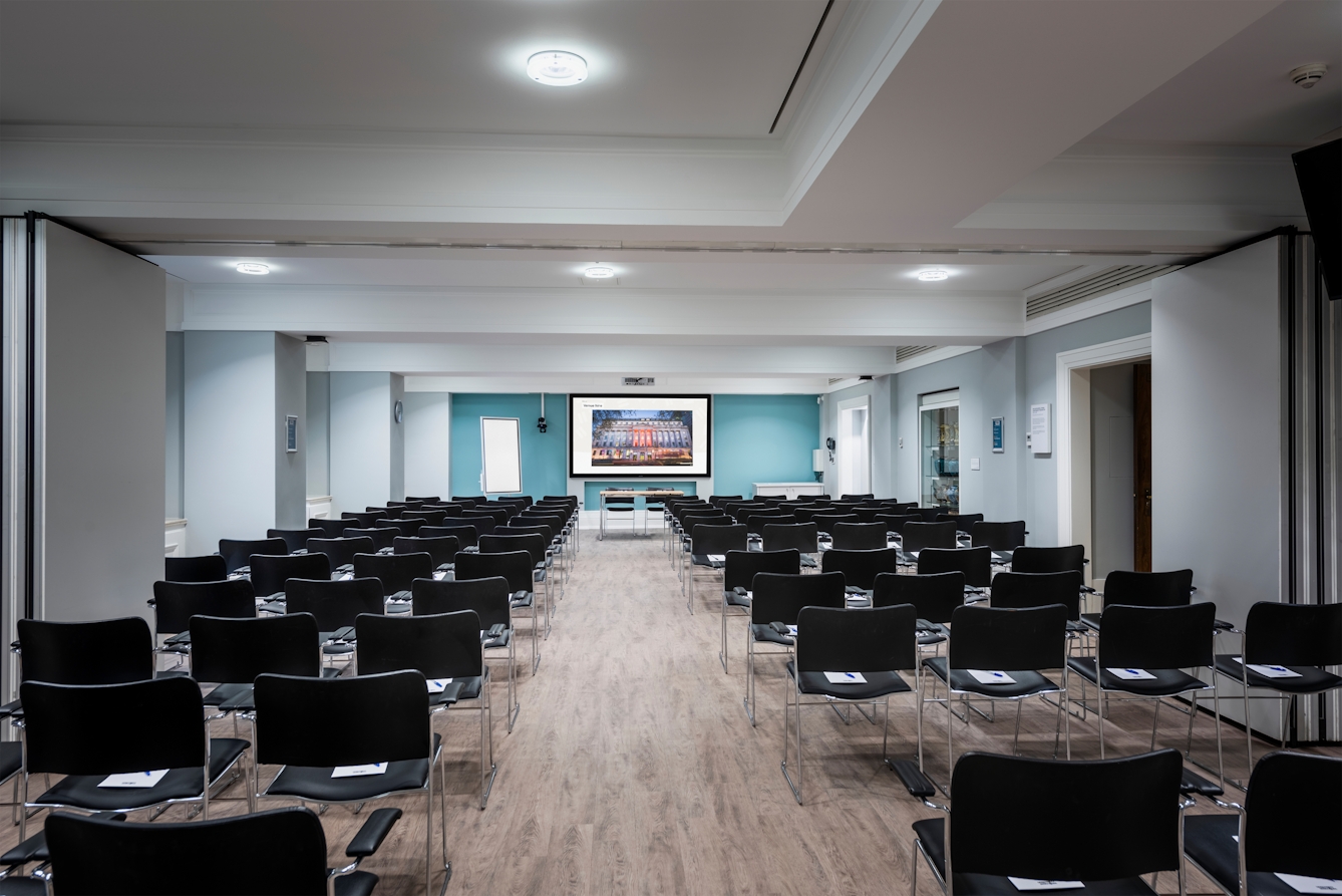 Photograph of the Franks and Steel room at the Wellcome Collection.
Photograph shows a theatre space with chairs and a projector and screen set-up.