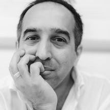 A headshot black and white photograph of a man resting his chin in his hand