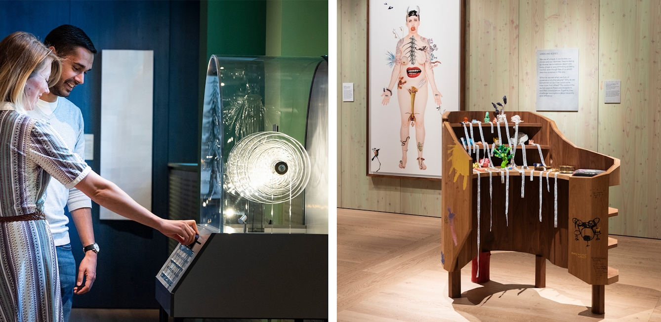 The photo on the left shows two visitors interacting with a jukebox. The bottom of the jukebox is made from metal and one of the visitors is pressing a button on it. The top of the jukebox is a glass dome shape and is filled with glass spiral shapes which are illuminated. The jukebox is a against a pastel green wall and there is a dark blue wooden panelled wall in the background on which exhibits hang. The photo on the right shows a rounded wooden desk with two shelves on the inside at seated level, on which there are various objects made from materials such as plasticine and resin with labels hanging off them and text written on them. There are also three shelves along the outside of the desk below waist level. In the background is a light pastel green wooden panelled wall on which a painting is hung. The painting is of a naked woman whose body is covered by various animals