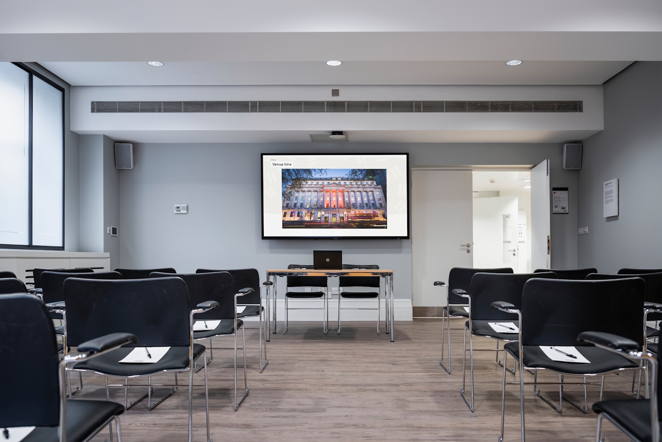 Photograph of the Dale room at the Wellcome Collection.
Photograph shows a theatre set-up with a desk and presenting screen at the front of the room.