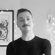 Black and white head and shoulders portrait of David Griffiths who has short brown hair a mustache and is wearing a black top.