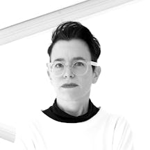 Black and white photograph of a white woman with short dark hair, wearing glasses and looking directly at the camera.