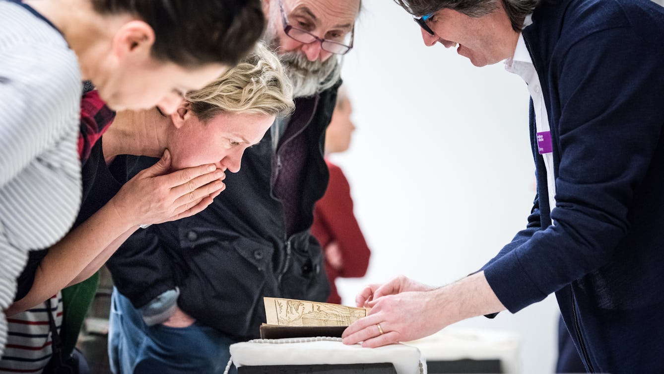 Photograph of a group of people examining library material on a table.
