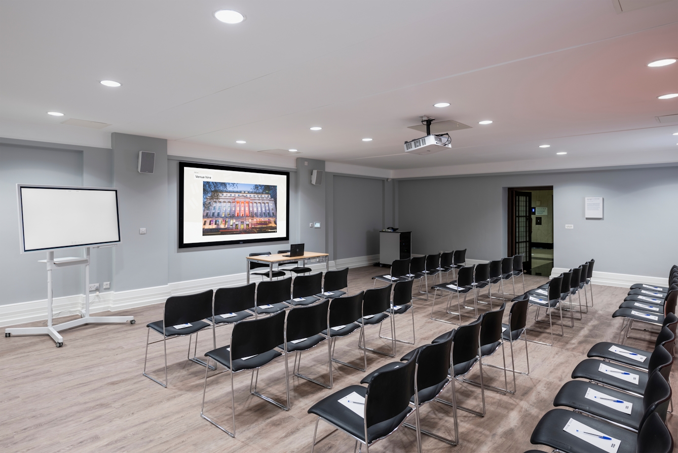 Photograph of the Burroughs room at the Wellcome Collection.
Photograph shows a theatre set-up, with a presenting screen and whiteboard at the front of the room.