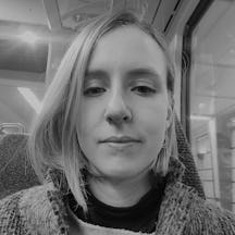Head and shoulders photograph of a woman on a train, with neck-length hair, falling forward over her right cheek 