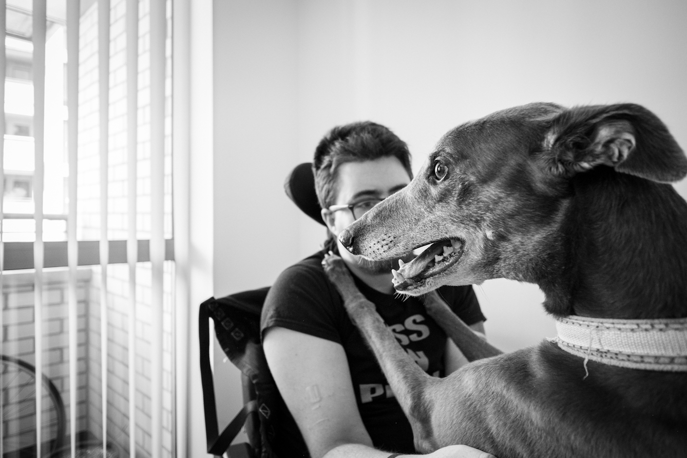 Black and white photograph of an individual with their greyhound.