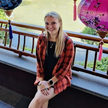 A photo of Daisy Watson Shaw sitting and smiling with a lake behind her.