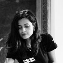 Black and white photo of the head and shoulders of a young woman with long black hair.